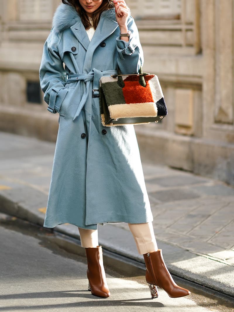 Women's outfit idea for 2022 with blue overcoat, neutral smart trousers, metallic earring. Suitable for fall and winter.