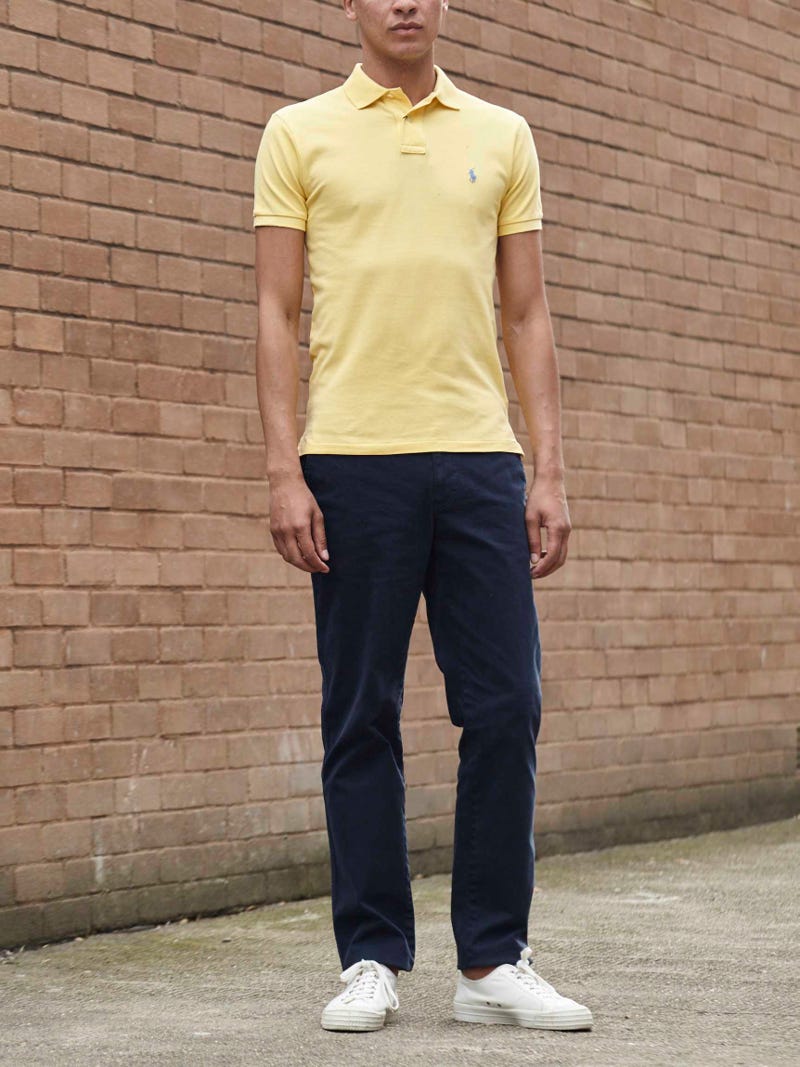 Men's outfit idea for 2022 with bold-colored polo, navy chinos, brown thick framed sunglasses, white sneakers. Suitable for summer.