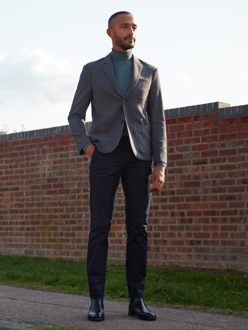Men's outfit idea for 2022 with grey blazer, green lightweight rollneck sweater, navy chinos, black chelsea boots. Suitable for spring, fall and winter.