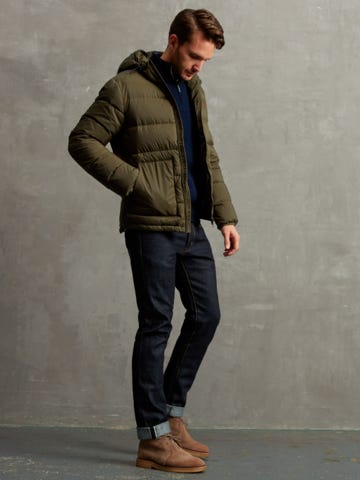 Men's outfit idea for 2022 with green down coat, half-zip / half-button sweater, dark blue jeans, brown desert boots. Suitable for fall and winter.
