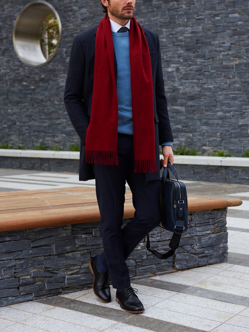 Men's outfit idea for 2022 with single-breasted overcoat, blue plain crew neck knitted sweater, navy dress pants, red plain knitted scarf, oxford / derby shoes. Suitable for fall and winter.