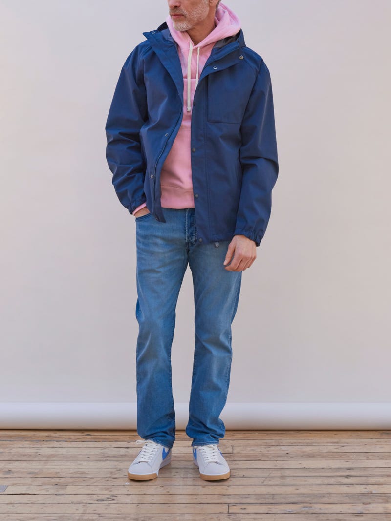 Men's outfit idea for 2022 with waterproof jacket / windbreaker, pink plain hoodie, mid blue jeans, white sneakers. Suitable for fall and winter.