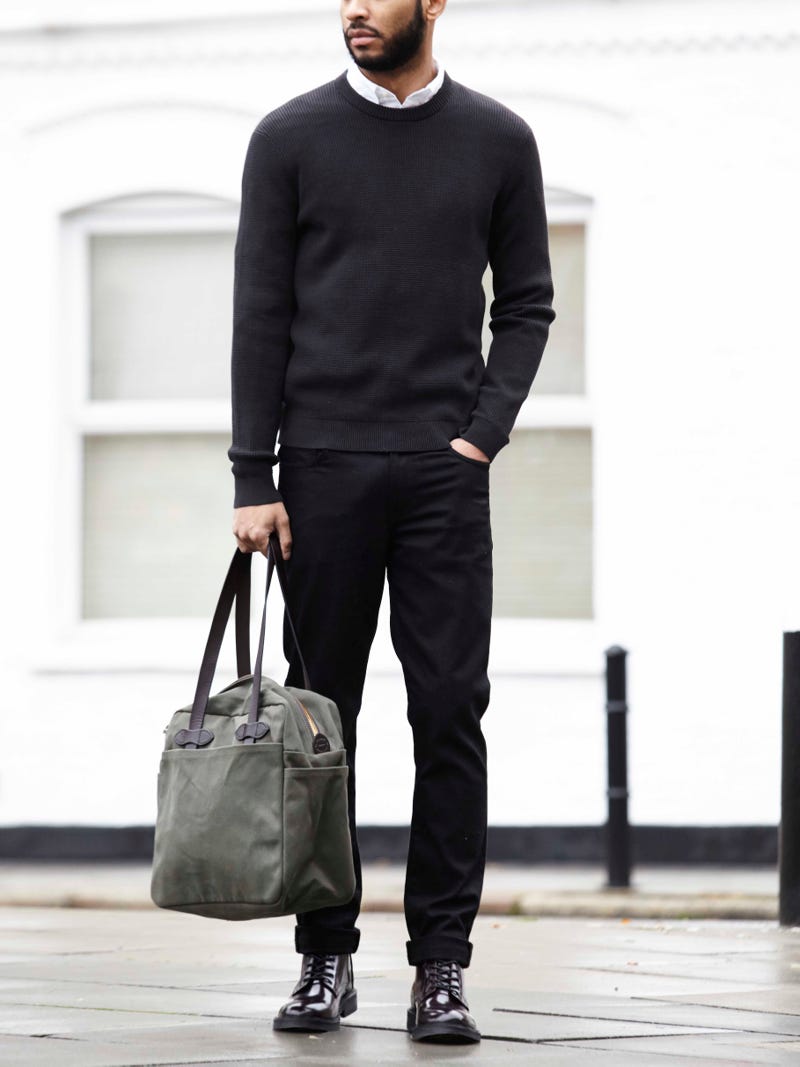 Men's outfit idea for 2022 with black crew neck knitted sweater, white casual shirt, black jeans, green tote bag, lace-up leather boots. Suitable for spring, fall and winter.