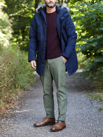 Men's outfit idea for 2022 with navy parka, cable-knit sweater, colored chinos, brown brogues. Suitable for fall and winter.