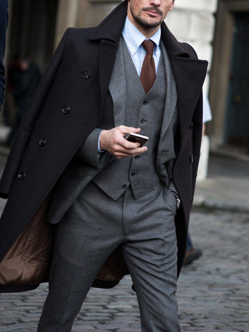 Men's outfit idea for 2022 with single-breasted overcoat, grey plaid suit, white dress shirt, knitted tie, oxford / derby shoes. Suitable for fall and winter.
