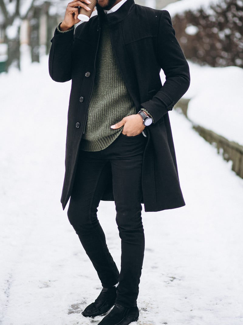 Men's outfit idea for 2022 with black single-breasted overcoat, green plain crew neck knitted sweater, white casual shirt, black jeans, black chelsea boots. Suitable for fall and winter.