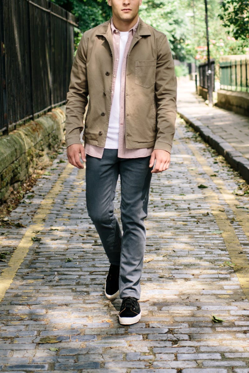 Men's outfit idea for 2022 with neutral utility jacket, pink casual shirt, white crew neck t-shirt, gray jeans	, black sneakers. Suitable for spring and fall.