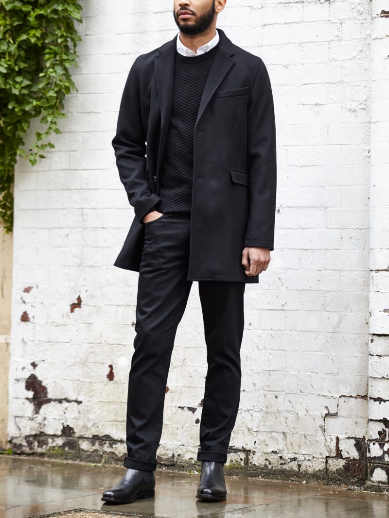 Men's outfit idea for 2022 with single-breasted overcoat, black crew neck knitted jumper, white casual shirt, black jeans, black chelsea boots. Suitable for spring, autumn and winter.
